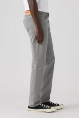 Pantalón de corte slim fit confeccionado en sarga de algodón con elastano, color gris. Presenta diseño clásico de cinco bolsillos, cierre de botón y cremallera, y costuras reforzadas.