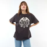 Camiseta de corte oversize color negro, con cuello redondo y mangas cortas. Presenta un estampado frontal en color crema con el logo de la banda Queen, rodeado de motivos florales y una corona.