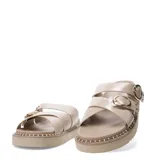 Sandalias planas Miss Carol modelo Zelv, color beige, con tiras anchas decoradas con hebillas metálicas doradas y tachas, sobre suela de plataforma baja con costuras visibles.