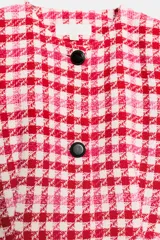 Blazer corto de tweed con estampado a cuadros en tonos rojo, rosado y blanco, cuello redondo, manga larga y cierre frontal con botones negros.