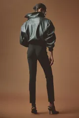 Pantalón de punto elástico en color negro, de corte ajustado con pliegue cosido frontal y cierre en los bajos.