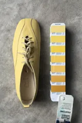 Zapato tipo flat de cuero amarillo con cordones frontales y punta cuadrada.