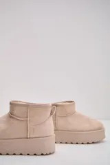 Bota corta tipo ugg de gamuza color beige, con plataforma plana y forro interior de piel sintética.