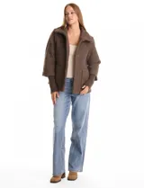 Tapado de tejido bouclé color marrón, con silueta evasé y largo a la cadera. Presenta cuello alto envolvente, cierre frontal oculto con botones a presión y bolsillos frontales de gran tamaño. Sus mangas son 3/4 con corte amplio y puños de tejido rib al tono que se extienden para cubrir las muñecas.