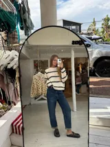 Buzo de tejido de punto grueso en color gris con rayas horizontales en color crema, de corte holgado, cuello redondo y mangas largas.