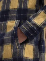 Sobrecamisa de tejido polar con estampado abstracto en tonos rojizos y azul marino. Presenta cuello clásico, cierre frontal con botones a presión, dos bolsillos frontales con solapa en el pecho y un parche decorativo.