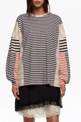 Remera manga larga oversize de corte relajado, confeccionada en 100% algodón orgánico con cuello redondo. Presenta un diseño de rayas horizontales en combinación de tonos azul marino, beige, blanco y detalles en rojo.