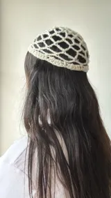 Gorro tipo bucket de crochet color crudo, con diseño de red y lentejuelas plateadas.