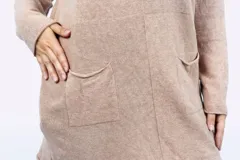 Buzo largo color beige, de corte holgado y mangas largas, con cuello en V y dos bolsillos delanteros.