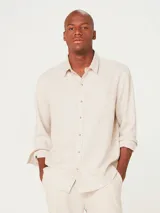 Camisa de manga larga en color gris, con cuello clásico, cierre frontal de botones y un bolsillo en el pecho.