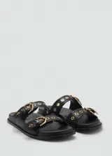 Sandalias planas de color negro con dos tiras en el empeine, cada una decorada con una hebilla metálica dorada y ojales.