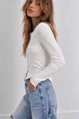 Blusa de punto color celeste con textura waffle, manga larga y cierre frontal de botones metálicos.