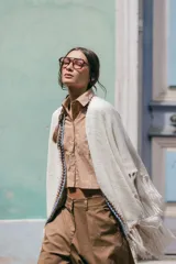 Poncho liviano de tejido de punto color blanco, con bordes decorados en crochet multicolor y flecos en el ruedo.