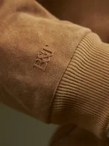 Campera bomber color camel de gamuza, con cierre frontal y bolsillos laterales.