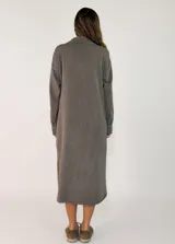 Vestido camisero midi de corte recto y holgado, con cierre frontal de botones, cuello camisero, mangas largas con puños abotonados y bolsillos frontales superiores con solapa.