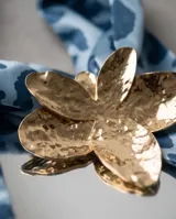 Pañuelo de seda celeste con estampado animal print azul y un dije metálico dorado en forma de flor que sujeta la prenda.