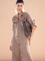 Vestido camisero largo color gris topo, de lino, con cuello camisero, mangas 3/4 con trabillas y bolsillos de parche en el pecho. Incluye cinturón de soga cruda con borlas.