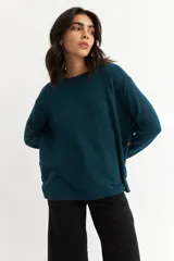 Sweater azul petróleo de tejido de punto, con cuello redondo y botones decorativos en los laterales.