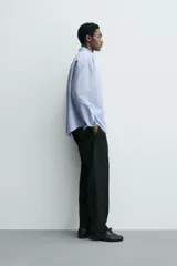 Pantalón de corte regular fit confeccionado en tejido mezcla de algodón. Presenta cintura con detalle de pliegues en el delantero, bolsillos frontales y bolsillos traseros de vivo con botón. Cierre frontal con cremallera y botón.