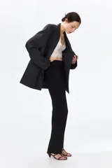 Leggings negros de punto pesado de corte sastre, con elástico oculto en la cintura, bolsillos decorativos en la parte trasera, pliegues cosidos al frente y pequeñas aberturas en los bajos.
