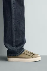 Zapatilla de cordones color negro con parte superior lisa, horma redonda y forro interior a contraste. Suela de goma color crema con ligera textura y detalle en el talón color crema.