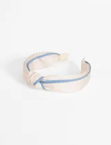 Vincha color beige con nudo superior y borde celeste.