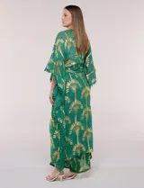Kimono largo de viscosa color verde con estampado metalizado dorado de palmeras, mangas anchas, detalles de pompones en los bordes y diseño abierto.