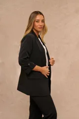 Blazer negro de corte recto con solapas, bolsillos frontales con solapa y mangas tres cuartos con detalle de botón.