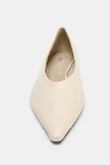 Zapato plano tipo bailarina confeccionado en piel de color beige, con escote redondo y acabado en punta fina.