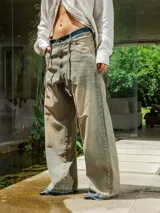 Pantalón de jean de lavado claro (oxido), corte ancho y tiro bajo, con cordones ajustables a la vista en la cintura y bordado en el frente.