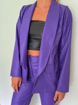 Blazer lila con textura croco, solapas amplias y bolsillos frontales.