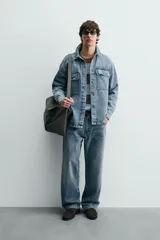Sobrecamisa de denim de algodón con efecto lavado, corte regular fit, cuello solapa, cierre frontal de botones, manga larga con puños abotonados y dos bolsillos frontales con solapa en el pecho.
