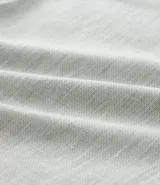 Bermuda de hombre en lino color gris claro, de corte recto, con textura discreta, bolsillos laterales y cierre frontal con botón y cremallera.