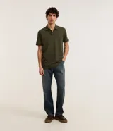 Remera polo de manga corta color verde militar, confeccionada en algodón peruano con cuello convencional y cierre de botones.