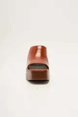 Zapato de plataforma tipo sueco, de empeine amplio en ante, con plataforma alta y taco ancho. Puntera cuadrada y diseño abierto en el talón.