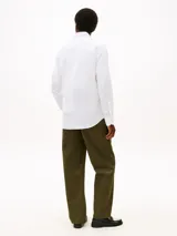 Camisa de corte regular de Tommy Hilfiger, confeccionada en sarga de algodón blanco, con cuello clásico, cierre frontal de botones y el característico logo bordado en el pecho.