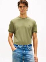 Remera de manga corta Tommy Hilfiger de corte slim en color verde militar, con cuello redondo clásico y detalle de doble raya blanca en los puños. Presenta el icónico logo de la marca bordado en el pecho.