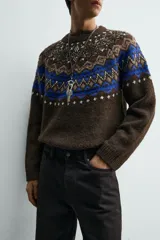 Jersey de punto con diseño jacquard geométrico en la parte superior, cuello redondo y manga larga. Presenta un corte relajado con acabados en rib en puños y ruedo.