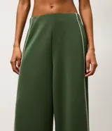 Pantalón deportivo ancho de color verde oscuro, de talle alto con cintura elástica y detalles de vivos en color blanco en los laterales y la botamanga.
