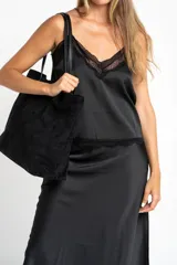 Blusa satinada negra con tirantes finos, escote en V y detalles de encaje en el escote y el dobladillo.