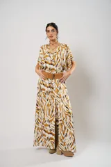 Vestido largo con estampado animal print en tonos camel, blanco y negro. Tiene escote en V, mangas cortas tipo murciélago y tajo frontal. Incluye cinturón ancho de cuero color camel.