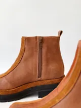 Botas cortas de cuero color marrón con elástico en los laterales y detalle de cuero texturizado en la parte delantera.