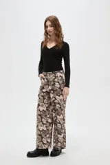 Pantalon de corte baggy con cintura media y bolsillos laterales. Presenta un estampado abstracto tipo camuflado en tonos tierra.