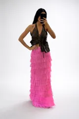 Pollera larga de tiro alto, confeccionada en capas de flecos color fucsia que crean un efecto de movimiento y textura.