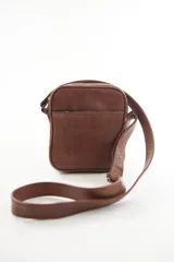 Morral bandolera de cuero genuino color marrón, con diseño compacto, cierre superior y correa ajustable para el hombro.