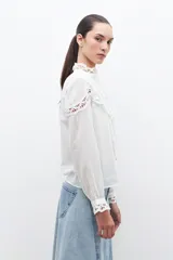 Camisa blanca de manga larga con cuello mao y puntilla calada en el frente y puños.