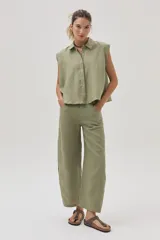 Blusa verde militar sin mangas, confeccionada en lino, con cuello camisero, cierre frontal con botones y corte holgado.