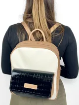 Mochila grande de cuero color beige, blanco y negro charol. Tiene un bolsillo frontal con cierre de broche imantado y logo grabado.