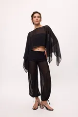 Pantalón ancho de seda color amarillo, estilo parachute o globo, con talle alto y cordones ajustables en los tobillos.