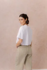 Remera crop color beige, de calce amplio, escote redondo y mangas cortas sueltas.